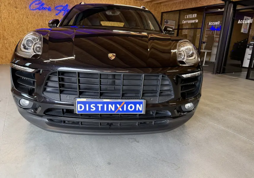 Vue avant d’un Porsche Macan S noir avec calandre large et phares bi-xénon, dans un showroom intérieur.