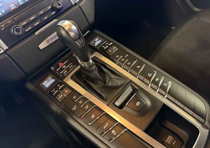 Gros plan sur la console centrale noire du Porsche Macan S avec levier de vitesse PDK et commandes tactiles.