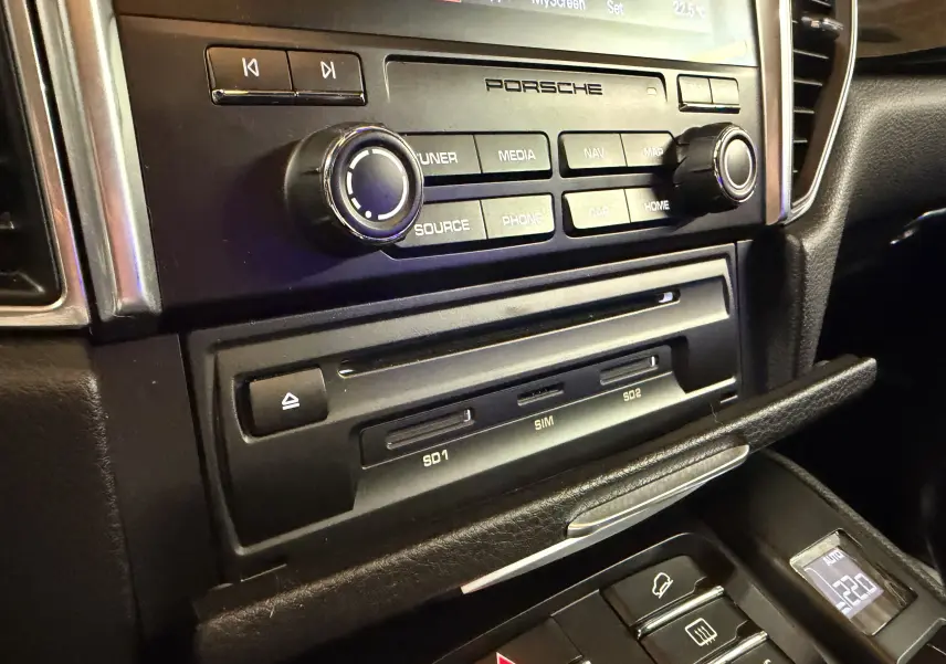 Gros plan sur la console centrale noire d’un Porsche Macan S, mettant en valeur les commandes multimédia et les ports SD.