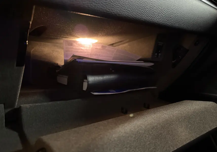 Gant de boîte à gants éclairé avec documents et manuel dans l'habitacle du Porsche Macan S noir.