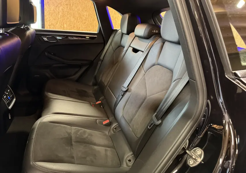 Vue intérieure côté droit des sièges arrière en cuir noir du Porsche Macan S 3.0i avec ceintures et appuie-têtes intégrés.