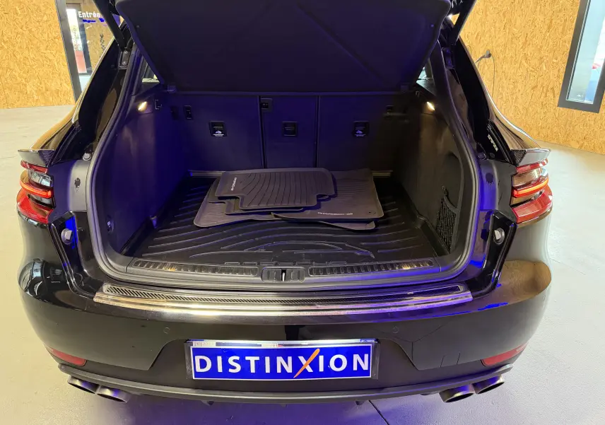 Coffre ouvert vu de l'arrière d'un Porsche Macan S noir avec tapis de sol Porsche et feux arrière LED visibles.