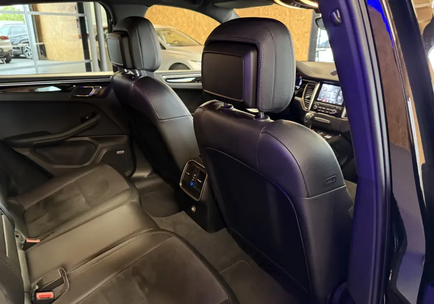 Vue intérieure arrière droite du Porsche Macan S noir, montrant les sièges en cuir et l'écran tactile du tableau de bord.