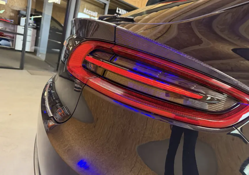 Gros plan sur le feu arrière droit rouge du Porsche Macan S noir, soulignant la finition brillante et la ligne sportive du coffre.