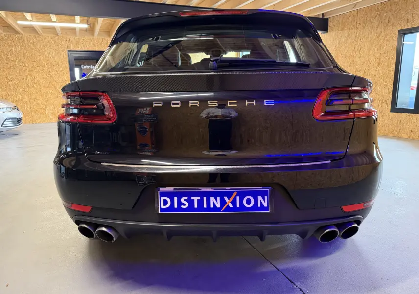 Vue arrière d'un Porsche Macan S noir avec feux LED, double sortie d'échappement sport et logo Porsche lumineux.