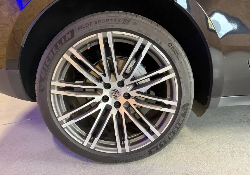 Gros plan sur la roue avant droite noire d'une Porsche Macan S avec jante alu 21 pouces et pneu Michelin Pilot Sport 4S.