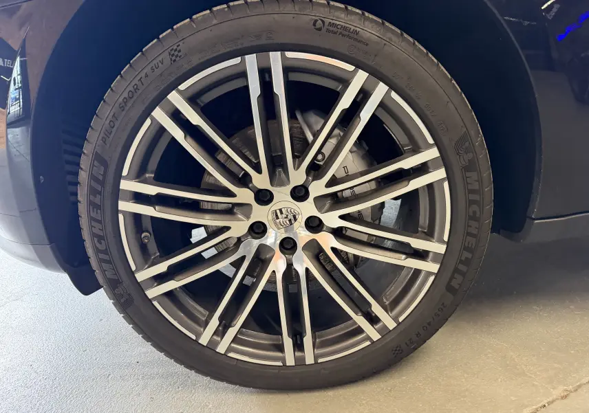 Gros plan sur la jante alu 21 pouces et pneu Michelin d'un Porsche Macan S noir, côté avant droit.