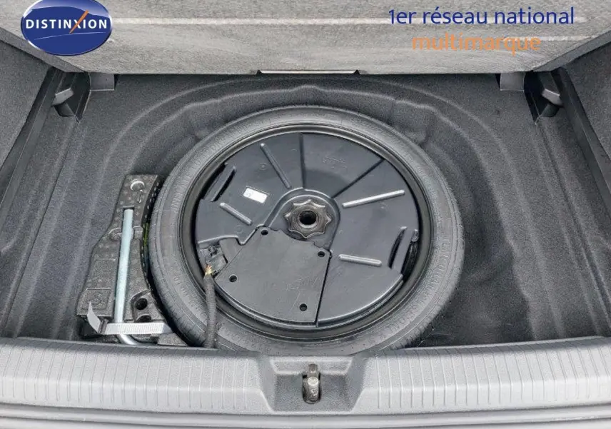 Vue plongeante sur la roue de secours et le compartiment de rangement dans le coffre d'une Volkswagen Golf noire 2024.