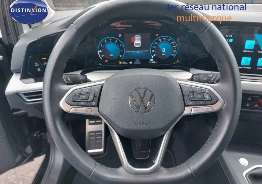 Vue rapprochée du volant noir de la Volkswagen Golf 1.5 TSI 150CH 2024 avec tableau de bord digital et commandes intégrées.