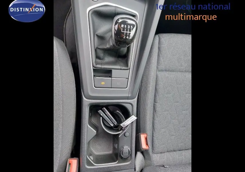 Vue plongeante sur la console centrale de la Volkswagen Golf noire, mettant en valeur le levier de vitesse manuel et les sièges tissu gris.