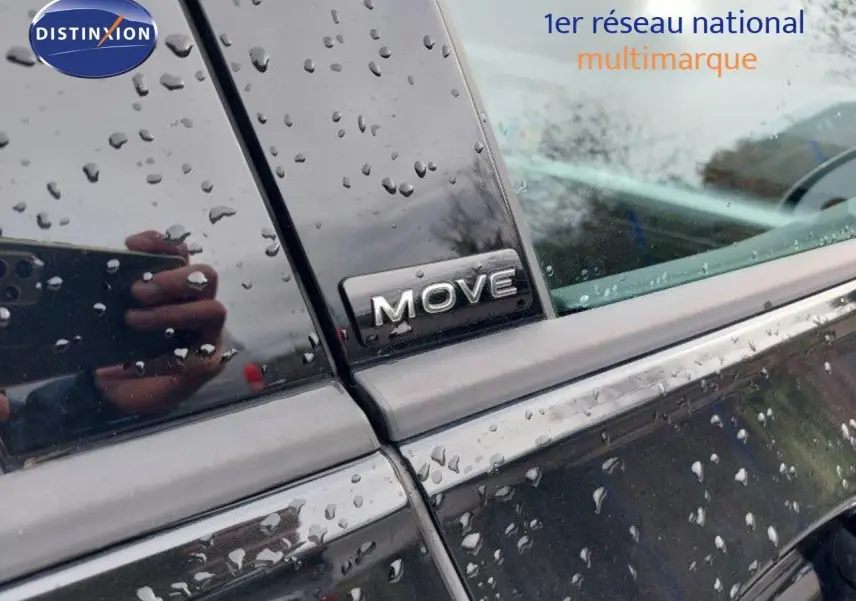 Gros plan sur l’inscription MOVE sur la portière arrière côté gauche d’une Volkswagen Golf noire métallisée sous la pluie.