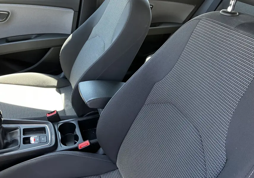 Gros plan sur les sièges avant en tissu noir et gris d'une SEAT LEON 1,6L TDI 115 STYLE de 2018, intérieur sobre et moderne.