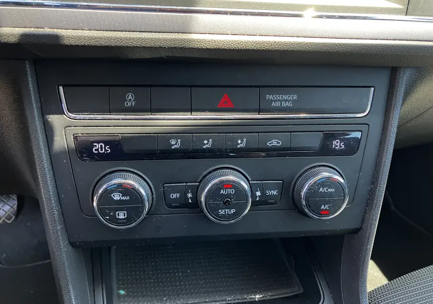 Tableau de bord noir de la SEAT LEON 2018, vue centrale sur les commandes de climatisation et boutons de sécurité.