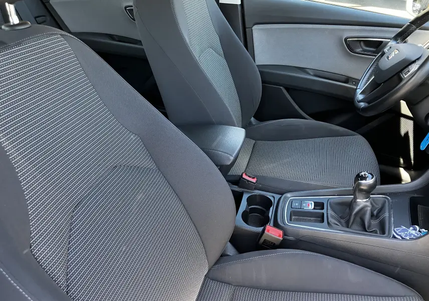 Vue intérieure côté conducteur du SEAT LEON noir 2018, montrant les sièges en tissu noir et la boîte manuelle.