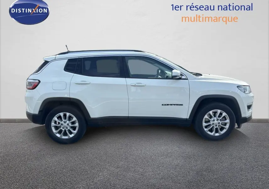 Profil côté droit d'un Jeep Compass blanc 2021 avec jantes alliage et détails noirs contrastants sur les passages de roue.
