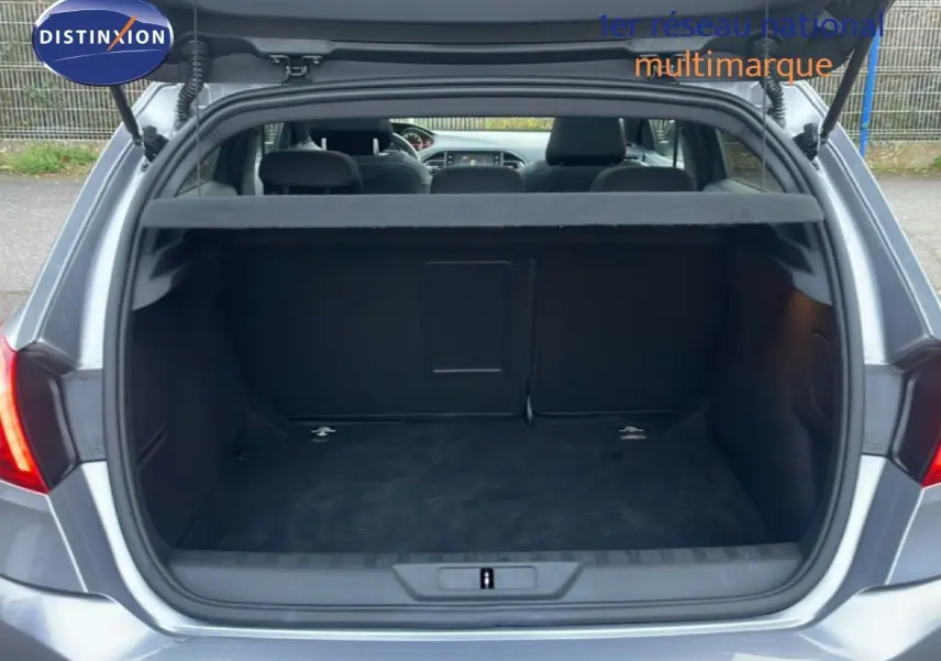 Vue arrière ouverte du coffre d'une Peugeot 308 gris Artense, montrant l'espace de chargement vide et la plage arrière.