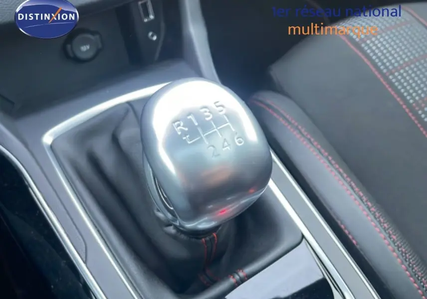 Gros plan sur le levier de vitesse manuel argenté de la Peugeot 308 gris Artense, avec couture rouge visible sur le siège à côté.