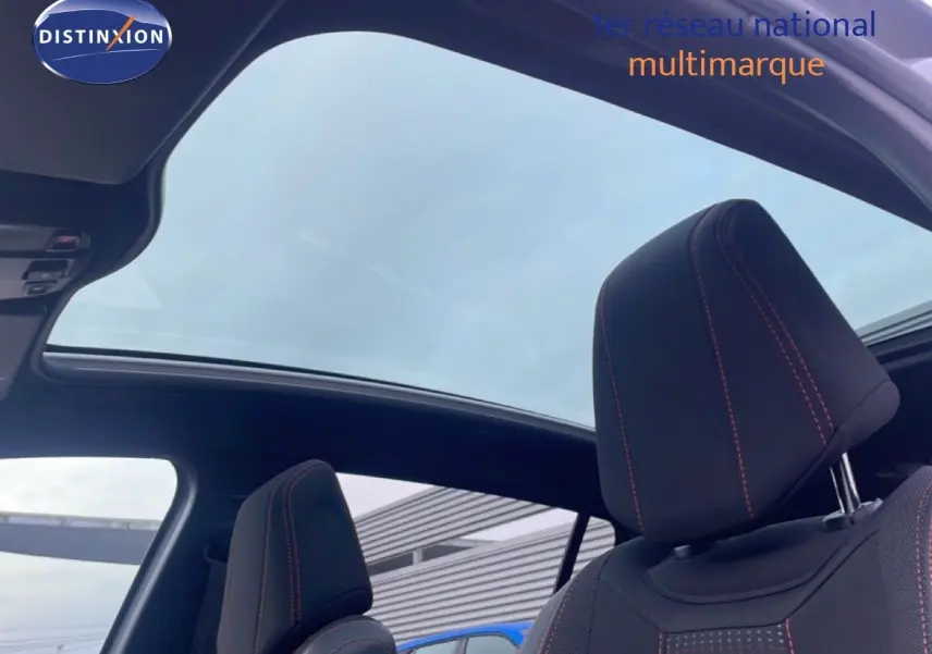 Vue intérieure sur les sièges avant noirs avec surpiqûres rouges et toit panoramique ouvert d'une Peugeot 308 gris Artense.