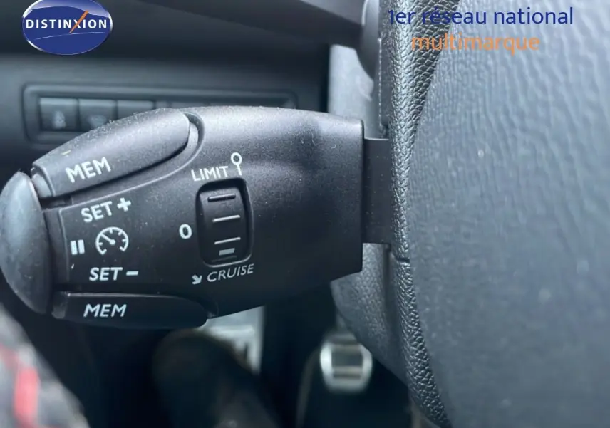 Gros plan sur la commande de régulateur de vitesse noire dans l'habitacle d'une Peugeot 308 gris Artense.