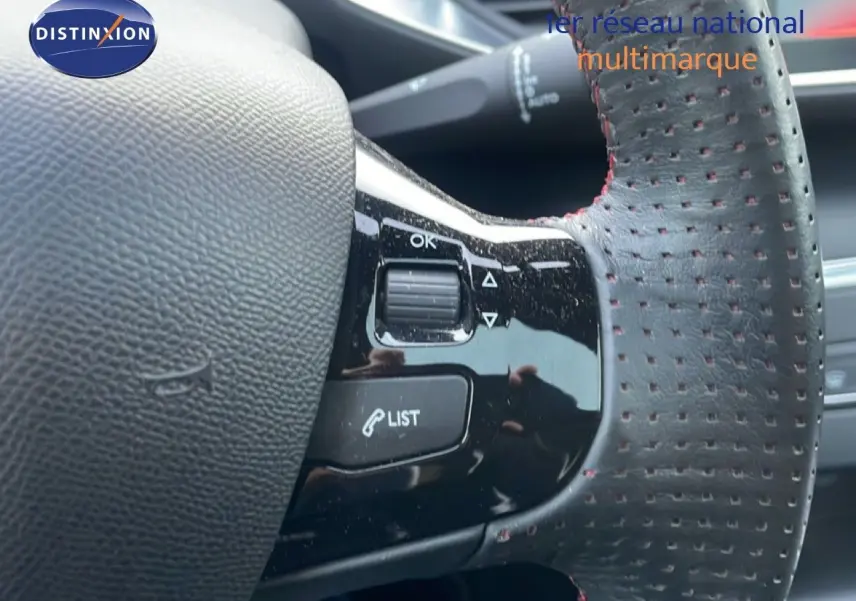 Gros plan sur le volant en cuir perforé avec surpiqûres rouges de la Peugeot 308 gris Artense, version GT Line 2017.