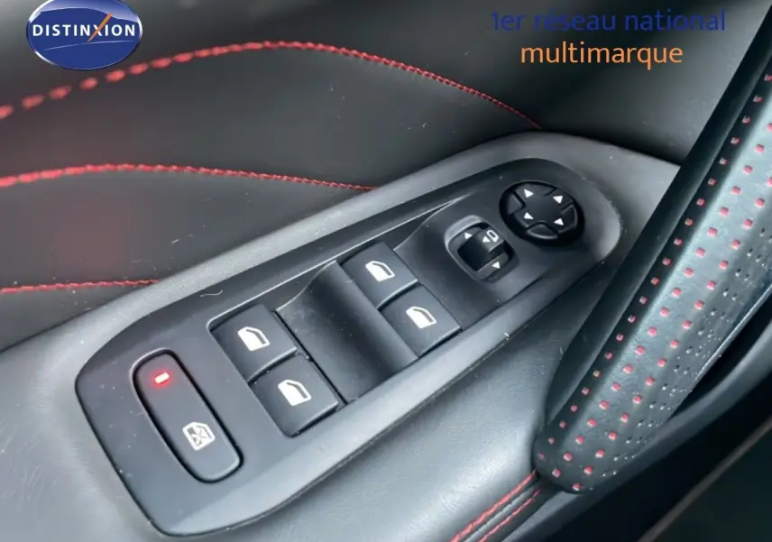 Gros plan sur les commandes de lève-vitres et réglages des rétroviseurs sur la porte côté gauche avec surpiqûres rouges.