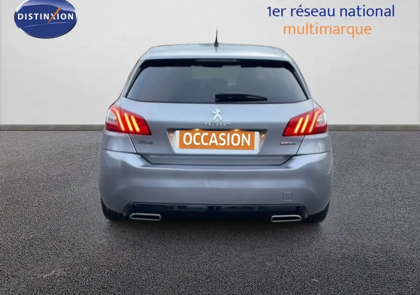 Vue arrière d'une Peugeot 308 gris Artense avec feux LED allumés et double sortie d'échappement chromée.