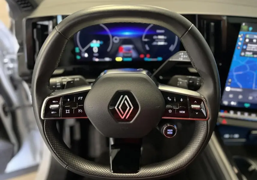 Volant en cuir noir avec logo Renault au centre, tableau de bord numérique et écran tactile du Renault Austral 2024 visible en arrière-plan