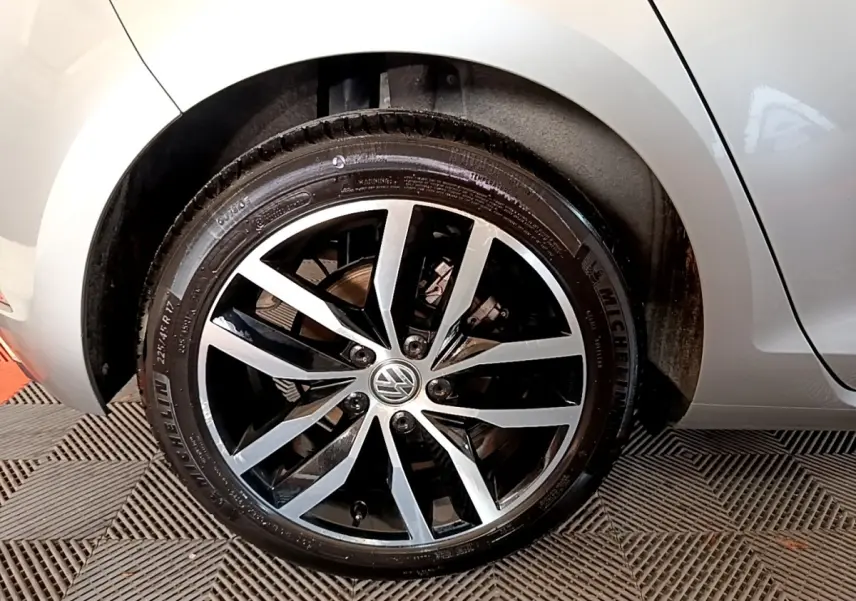 Gros plan sur la roue avant droite gris clair de la Volkswagen Golf 1.6 TDI avec jante alliage bicolore et logo VW central.