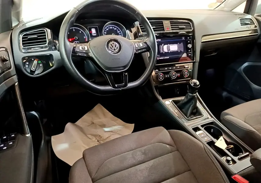 Intérieur de Volkswagen Golf 2017 vu côté conducteur, volant cuir, tableau de bord avec écran tactile et boîte manuelle.