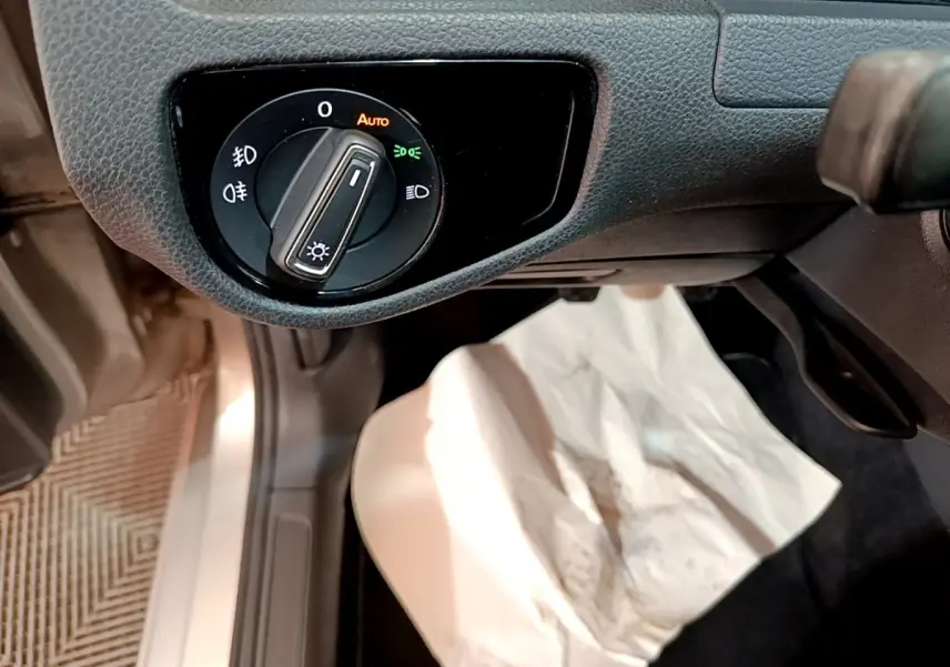 Gros plan sur la commande d’éclairage côté gauche du tableau de bord d’une Volkswagen Golf gris clair de 2017.