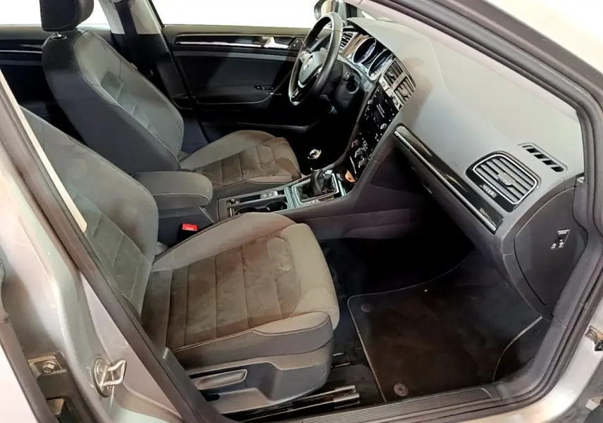 Intérieur avant droit d'une Volkswagen Golf gris clair 2017, sièges tissu et console centrale avec boîte manuelle.