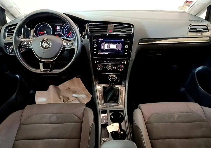Vue intérieure avant de la Volkswagen Golf 1.6 TDI 2017, tableau de bord noir avec écran tactile et volant cuir multifonctions.