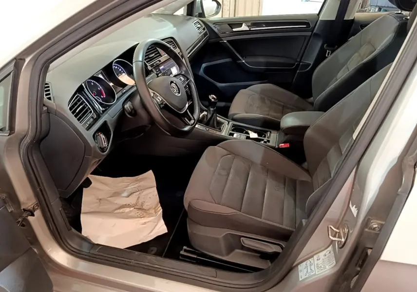 Vue intérieure côté conducteur de la Volkswagen Golf gris clair 2017, montrant sièges et tableau de bord noir.