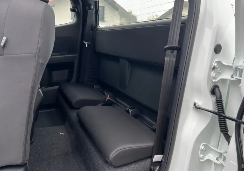 Vue intérieure arrière côté droit du pick-up Isuzu D-MAX Splash White, montrant les strapontins et la porte ouverte.