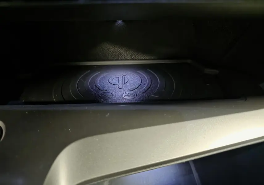 Gros plan sur le chargeur à induction pour smartphone dans l'habitacle de la Peugeot 408 gris, version hybride 2025.