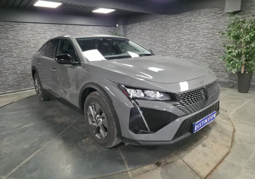 Peugeot 408 gris vue 3/4 avant droit en intérieur avec calandre noire et jantes alliage 17 pouces.