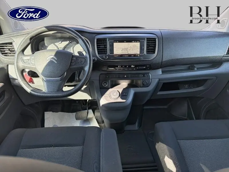 Vue intérieure avant du poste de conduite du Citroën Jumpy blanc, avec volant multifonction et écran tactile central.