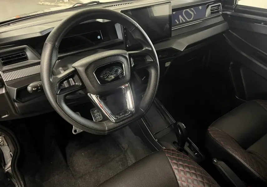 Vue intérieure du tableau de bord et volant noir du Ligier JS50 0.5 REVO D+ Ultimate avec écran tactile central.