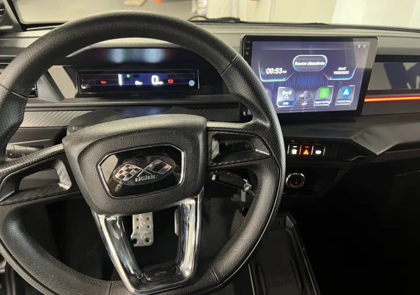 Vue intérieure centrée sur le volant noir et le tableau de bord digital du Ligier JS50 bleu 2026.