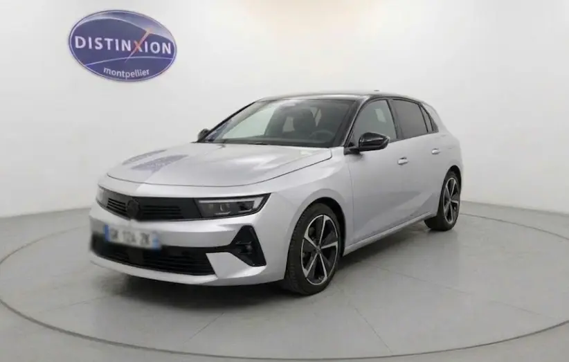 Opel Astra 2024 gris en 3/4 avant droit, avec jantes alliage noires et phares LED modernes visibles.