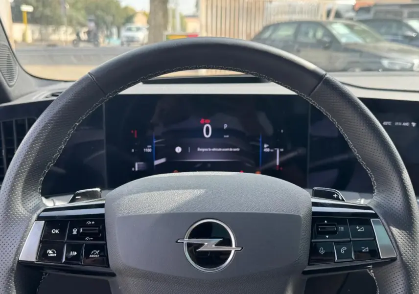 Vue rapprochée du volant cuir gris de l’Opel Astra 2024 avec commandes intégrées et tableau de bord digital.