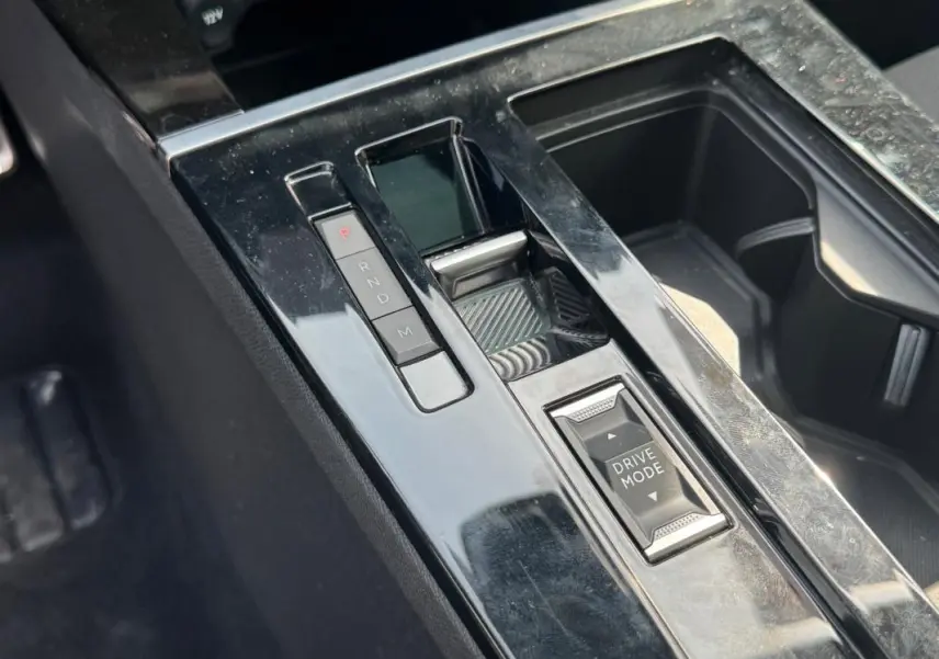 Gros plan sur la console centrale noire brillante de l’Opel Astra 2024 avec sélecteur de mode de conduite et boutons de boîte auto.