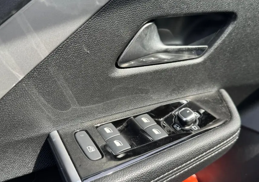 Gros plan sur la commande des vitres électriques et rétroviseurs côté conducteur d’une Opel Astra gris 2024.