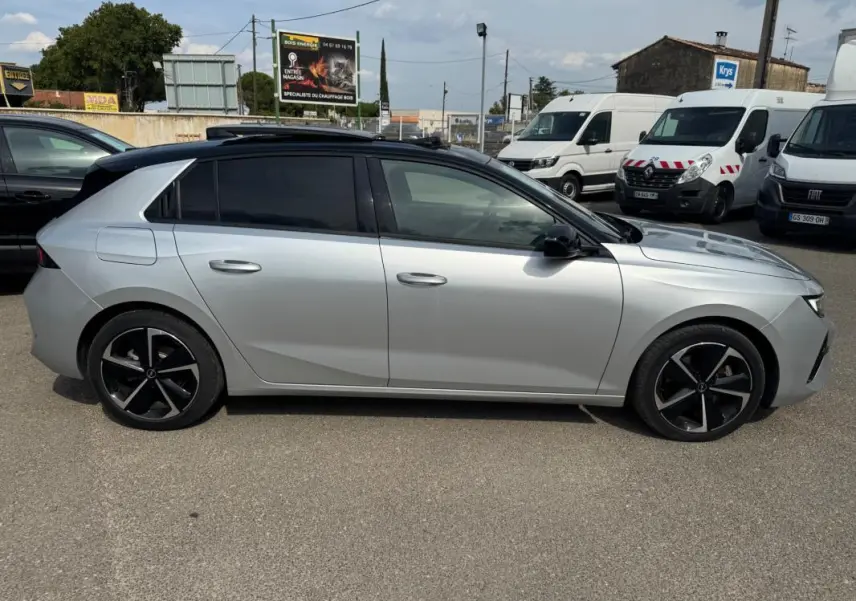 Opel Astra 2024 gris en profil côté gauche, avec jantes alliage noires et vitres surteintées.