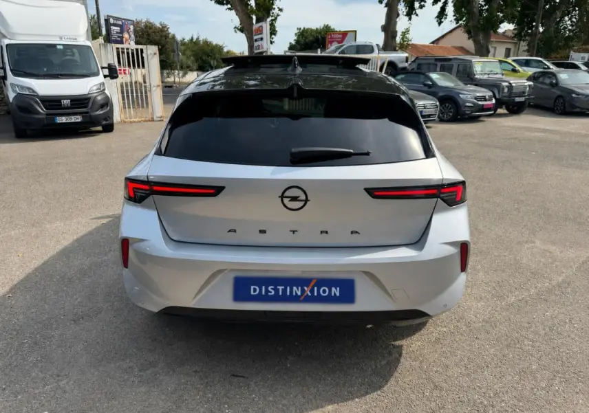 Vue arrière d'une Opel Astra gris clair 2024 avec feux LED horizontaux et vitres surteintées.