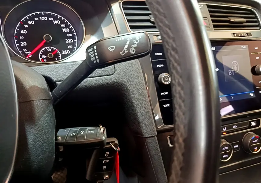 Vue rapprochée du tableau de bord et volant cuir d'une Volkswagen Golf noire, avec écran tactile et commandes au volant visibles.