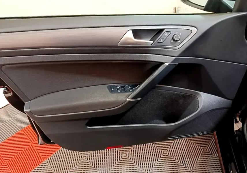 Vue rapprochée de la porte avant gauche noire de la Volkswagen Golf 2018, avec commandes électriques et insert décoratif gris.