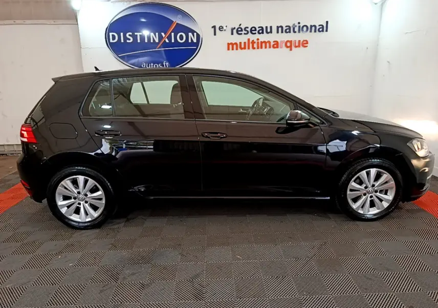 Profil côté gauche d'une Volkswagen Golf noire 2018, version Confort Business, dans un showroom lumineux.