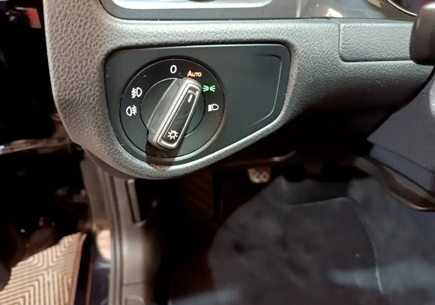 Gros plan sur le bouton de commande des phares dans l'habitacle noir de la Volkswagen Golf 1.6 TDI 2018 côté gauche.