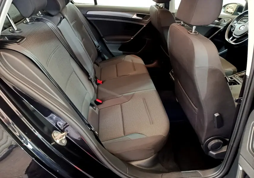 Vue intérieure côté droit sur la banquette arrière et l'avant d'une Volkswagen Golf noire de 2018, sièges tissu gris.